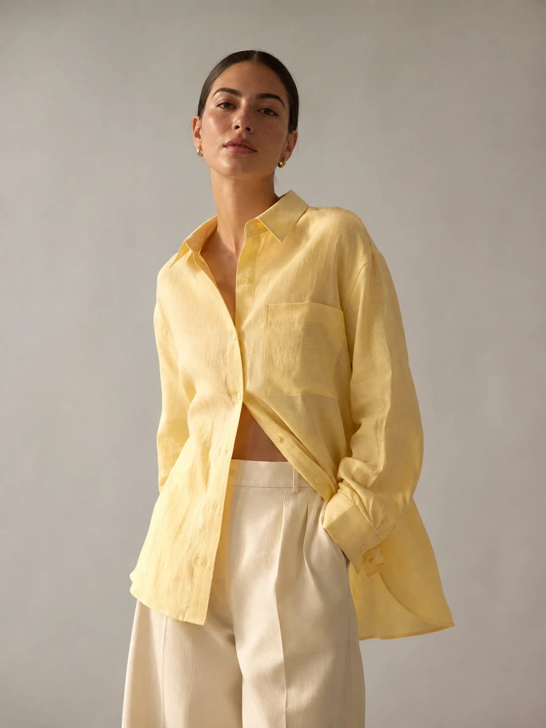Illustrative fashion campaign: an AI model wearing a butter-yellow linen shirt and cream trousers